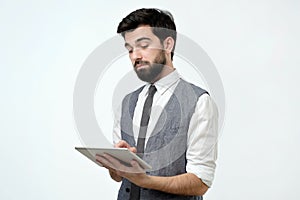 Pensive young handsome man using his digital tablet surfing in internet