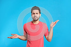 Pensive young man on blue background. Thinking about difficult question