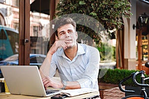 Pensive young stylish man in shirt working on laptop