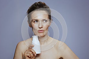 pensive young woman with cosmetic cream jar