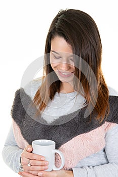 Pensive young woman with cup of tea looks down in sweater pink