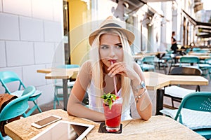 Pensive young woman drinking cocktail and thinking in outdoor cafe