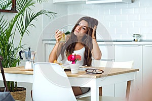 Pensive young woman drinking juice in the kitchen.