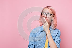 Pensive young woman with dyed pink hair looking up