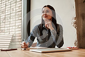 pensive young woman holding pen near