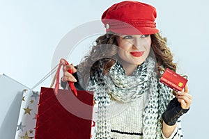 Pensive woman shopper isolated on winter light blue background