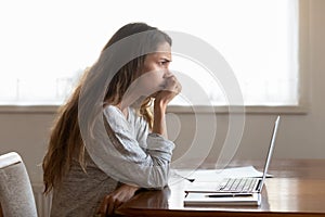 Pensive young woman lost in thoughts pondering over problem