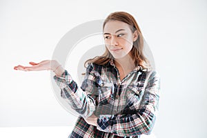 Pensive young woman in plaid shirt holding copyspace on palm