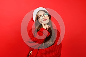 Pensive young woman on a red background, dreamy emotions