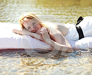 Pensive young woman relaxing in bed outdoors on water