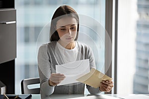 Pensive young woman read postal letter in office photo