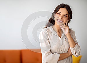 Pensive young woman smiling gently and looking away at copy space