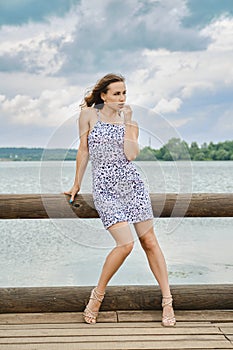 Pensive young woman touching her lip and looking away at lake