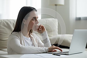 Pensive young woman work on laptop thinking