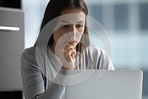 Pensive young woman work on laptop thinking of problem solution