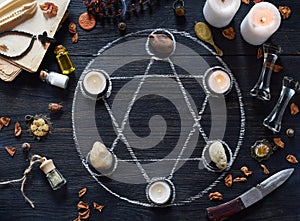 Pentagram circle with candles, stones, love potion and old books on witch table. Occult, esoteric or divination concept. Mystic,