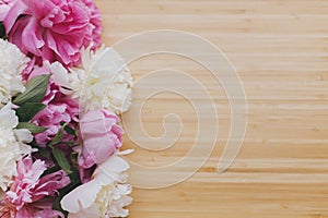 Peony bouquet on wooden background top view with space for text. Pink and white peonies flowers