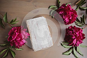 Peony flowers and old book on vintage wooden background