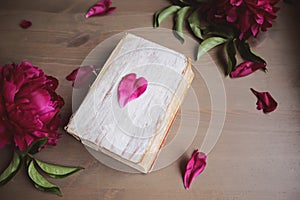 Peony flowers and old book on vintage wooden background