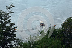 Peopl sailing in a boat on a calm sea to deploy fishing nets on a cloudy day