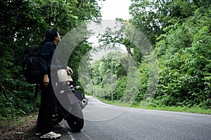 people activity concept with asian man biker take picture in tropical forest with his motorcycle