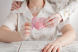 People, age, family, love and health care concept - close up of senior woman and young woman hands holding red heart