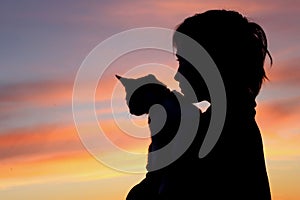 People, animals, pets, childhood concept. Silhouette of an owner and pet. Silhouette of young girl holding a cat, cropped shot.