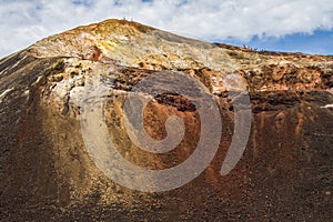 People appear tiny standing on top of a volcano