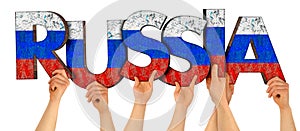 People arms hands holding up wooden letter lettering forming word RUSSIA in russian national flag colors  white blue and red. war