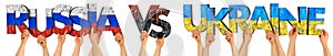 People arms hands holding up wooden letter lettering forming words RUSSIA VS UKRAINE in russian and ukrainian flag colors.