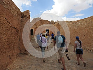 People, back view, go to the mountain oasis of Chebika with palm trees in the sandy Sahara desert, blue blue sky, Tunisia, Africa