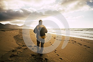 People in back view walking alone with his backpack on the desolation beautiful wild beach for alternative concept of tourism