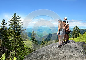 People with backpacks hiking on summer trip in mountains.