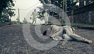 People in bacteriological protective suits running to help a woman