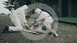 People in bacteriological protective suits running to help a woman