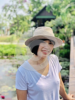 Outdoors close up portrait of girl smiling or Asian woman smiling in the park and looking at camera