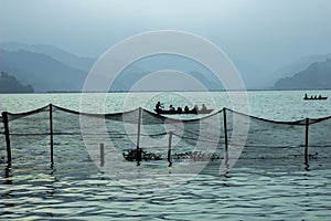 A people in a boat on the lake against the evening silhouettes of mountains. fishing net on the water