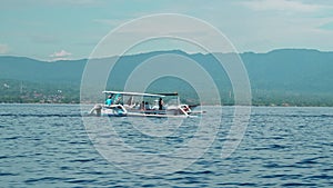 People on a boat sail behind the Stenellalongirostris family of dolphins that jump out of the water in the open, clear sea on the