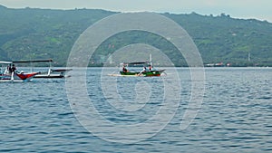 People on a boat sail behind the Stenellalongirostris family of dolphins that jump out of the water in the open, clear sea on the