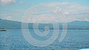 People on a boat sail behind the Stenellalongirostris family of dolphins that jump out of the water in the open, clear sea on the