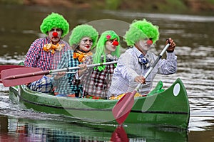 People boating on river. People are dressed for clowns in boat.