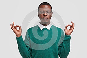 People, body language and meditation concept. Relaxed dark skinned African American man has calm facial expression