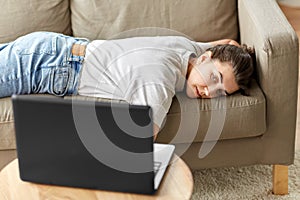 Bored woman with laptop lying on sofa at home