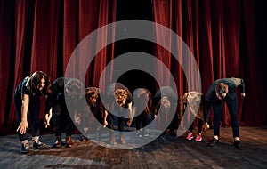 People bowing to audience. Group of actors in dark colored clothes on rehearsal in the theater