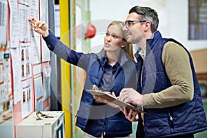 People, business and checking schedule with board in warehouse with calendar for order details. Man, woman and together