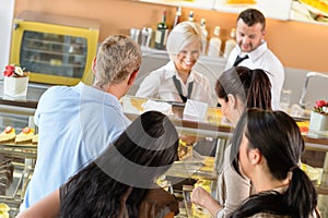 People buying cakes at cafeteria queue desserts