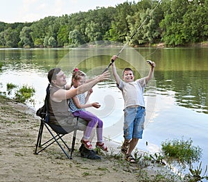 People camping and fishing, family active in nature, fish caught on bait, river and forest, summer season