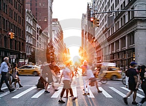 People, cars, taxis and bikes in the busy intersection of 5th Avenue and 23rd Street in New York City with summer sunset shining