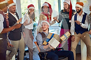 People celebrating winter holidays together at work. Happy business people in santa hat