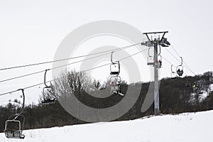 People On A Chairlift Ascend A Ski Slope photo
